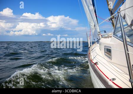Yacht à voile de luxe sous gênes et grand voile coupant à travers les vagues de la mer Baltique, golfe de Finlande. Vue du pont à la proue, mât et voiles, emphas Banque D'Images
