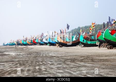 Cox's Bazar, Bangladesh - 06 février 2024 : vue sur les bateaux de pêche animés alignés soigneusement le long de la plage Cox's Bazar - Teknaf Highway, leurs coques colorées contrastant avec le sable sombre. Banque D'Images
