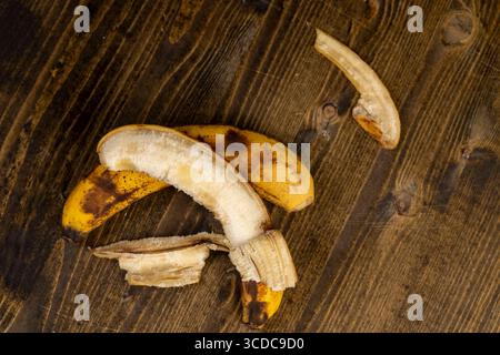 banane mûre ancienne surmûre noircie pendant le stockage sur une planche de pin noir, banane pourrie noircie sur une table en bois Banque D'Images
