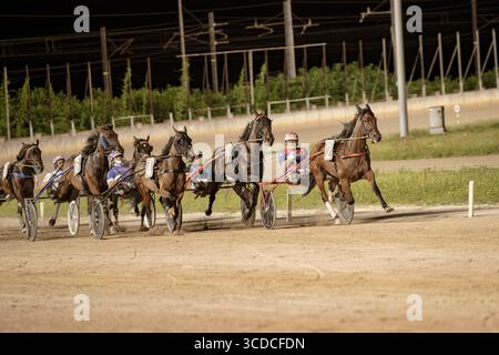 Padoue, italie 18 juillet 2025, chevaux de course attelés courant sur piste la nuit en compétition pour la victoire Banque D'Images