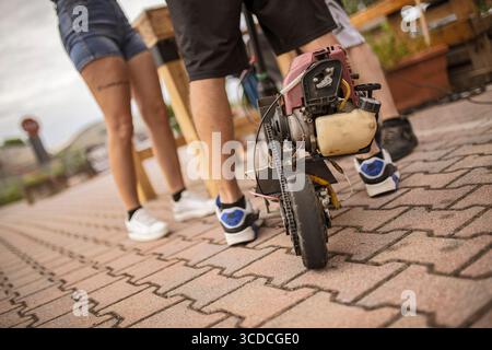 Rome, italie 18 juillet 2025, deux mécaniciens montrent leur moto miniature fabriquée par eux-mêmes avec un moteur à combustion visible et une transmission par chaîne Banque D'Images