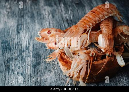 galeras espagnoles fraîches, squilla mantis crustacés, empilés dans un bol en bois placé sur une surface de table en bois bleu rustique à l'intérieur pour la préparation culinaire Banque D'Images