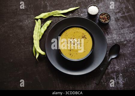 Nourriture saine. Soupe crémeuse aux haricots verts dans un bol noir en céramique sur une table rustique sombre. Le concept de régime alimentaire Banque D'Images
