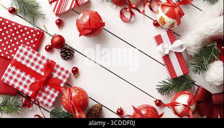 D'en haut photo de diverses décorations de Noël mignon et joliment emballé cadeaux formant frontière mignon blanc sur fond de bois Banque D'Images