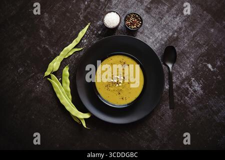 Nourriture saine. Soupe crémeuse aux haricots verts dans un bol noir en céramique sur une table rustique sombre. Le concept de régime alimentaire Banque D'Images