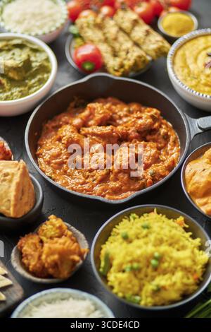 Divers plats indiens sur une table. Poulet épicé Tikka Masala dans une poêle en fer. Servi avec riz, naan et épices. Ensemble de différents types de nourriture indienne Banque D'Images