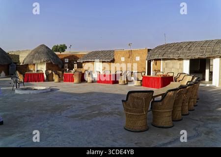 Village de tentes touristiques dans le désert du Thar, près de Jaisalmer, Rajasthan, Inde du Nord, une cour ouverte avec des bâtiments traditionnels, des tables meublées et ch Banque D'Images