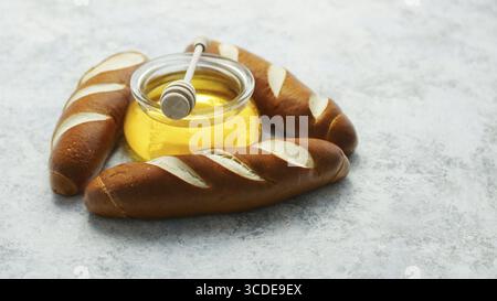 Disposition des baguettes d'or de triangle avec pot de miel en verre au milieu de la surface gris Banque D'Images