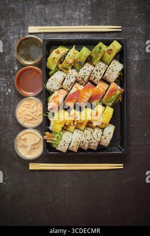 Cuisine asiatique, divers ensembles de sushi dans des récipients en plastique avec sauces, riz et baguettes. Vue de dessus, plan d'appartement Banque D'Images