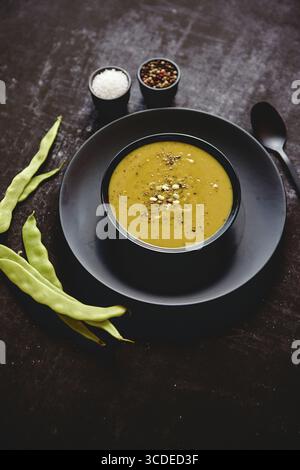 Nourriture saine. Soupe crémeuse aux haricots verts dans un bol noir en céramique sur une table rustique sombre. Le concept de régime alimentaire Banque D'Images