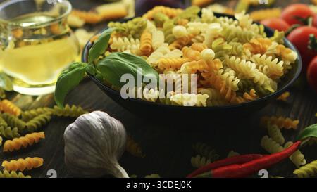 Big Black bowl full of macaroni aux légumes spirale colorée placée près de sur la table en bois Banque D'Images