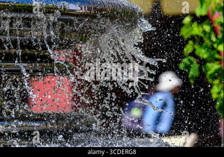 Chemnitz, Allemagne. 13 août 2025. Un passant vêtu d'un chapeau de soleil passe devant une fontaine sur la place du marché à Chemnitz. À des températures d'environ 30 degrés Celsius, les caractéristiques de l'eau offrent un moyen bienvenu de se rafraîchir. Crédit : Hendrik Schmidt/dpa/Alamy Live News Banque D'Images