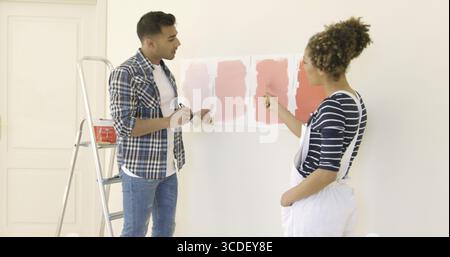 Jeune couple de débattre une nouvelle couleur de peinture pour le mur de leur maison comme ils s'engager dans un projet de rénovation Banque D'Images