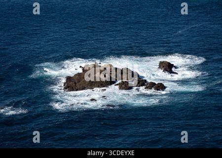 Île rocheuse entourée de vagues océaniques Banque D'Images