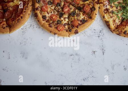 Trois sortes différentes de pizzas. Placé dans une rangée sur la table rouillée blanche. Vue de dessus avec un espace pour votre texte Banque D'Images
