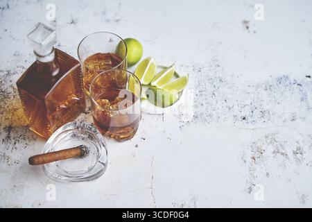 Boisson aigre de whisky avec citron vert dans le verre sur fond rustique de pierre. Deux verres remplis de glace et carafe Banque D'Images