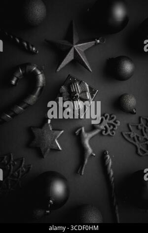 Composition minimaliste et simple de Noël en couleur noir mat. Cadeaux de Noël, décorations sur fond noir. Plat, vue de dessus Banque D'Images