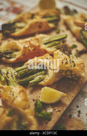 Asperges vertes cuites enveloppées de pâte feuilletée. Servi en bois. Vue de dessus, plan d'appartement. Mise au point sélective Banque D'Images