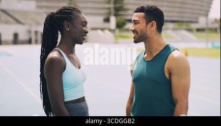 Parler, les gens ou l'athlète sur la bonne voie pour la pause, l'exercice ou la forme physique pour le bien-être ou le travail d'équipe. Chat, coureurs ou femme avec homme dans le stade pour le sport Banque D'Images