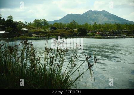 Un village rural tranquille au bord du lac avec une montagne volcanique en toile de fond Banque D'Images