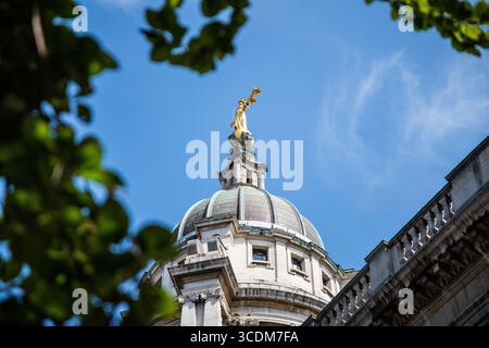 Regardant la statue dorée de Lady Justice au sommet de la Cour pénale centrale de Londres, face à un ciel bleu lumineux d'été. Banque D'Images