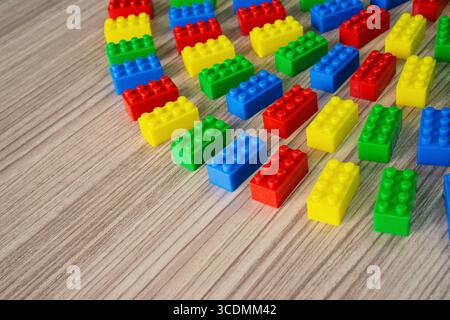 Blocs de construction en plastique coloré disposés en courbe sur une surface en bois avec espace de copie. Banque D'Images