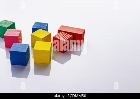 Blocs de bois colorés disposés sur une surface blanche. Banque D'Images