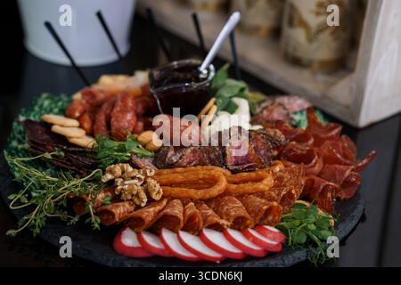 Une planche de charcuterie magnifiquement arrangée avec salami, prosciutto, bresaola, noix, fromages, et les baies, présentées sur un plateau d'ardoise, parfaites Banque D'Images