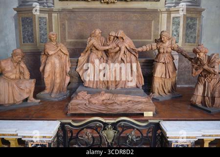 Une sculpture en terre cuite d'une Vierge Marie pleurant à côté de bougies votives. À la Metropolitana di San Pietro, cathédrale Saint-Pierre, à Bologne, Italie. Banque D'Images