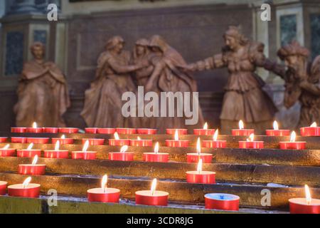 Une sculpture en terre cuite d'une Vierge Marie pleurant à côté de bougies votives. À la Metropolitana di San Pietro, cathédrale Saint-Pierre, à Bologne, Italie. Banque D'Images