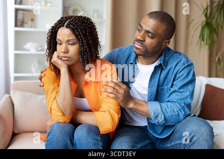 Homme noir attentionné réconfortant sa triste petite amie à la maison, montrant un soutien émotionnel Banque D'Images