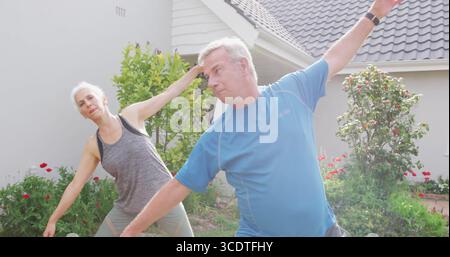 Couple d'étirements portant des vêtements de sport faisant des étirements latéraux sur la pelouse, avec tracker de fitness Banque D'Images