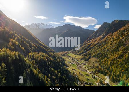 Vue aérienne de la lumière dorée du soleil illuminant la vallée sous les sommets enneigés du Mont Blanc, projetant de longues ombres sur le paysage automnal, Chamonix, Auvergne-Rhône-Alpes, France. Banque D'Images