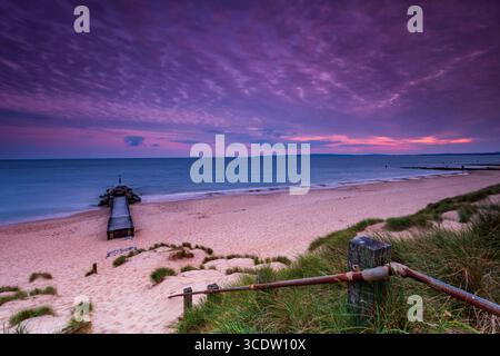 Eaux calmes à Southbourne plage illuminée par le soleil couchant au coucher du soleil Banque D'Images
