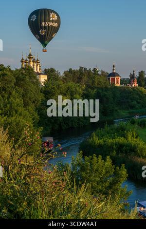 Souzdal, région de Vladimir, Russie - 07.24.2025. La montgolfière flotte gracieusement au-dessus de Souzdal, mettant en valeur ses églises emblématiques et une rive sereine de Kamenka Banque D'Images