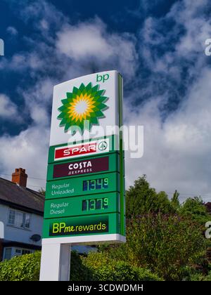 Bishop's Castle, Royaume-Uni - 04 août 2025 : panneau de prix du carburant BP avec les logos SPAR et Costa Express sur un ciel bleu vif au château de Bishop, Royaume-Uni, capturé dans une lumière de midi. Banque D'Images