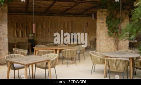 Ambiance floue en terrasse avec chaises et tables défocalisées dans un restaurant de style méditerranéen aux tons chauds et à l'effet bokeh pour un dîner détendu Banque D'Images