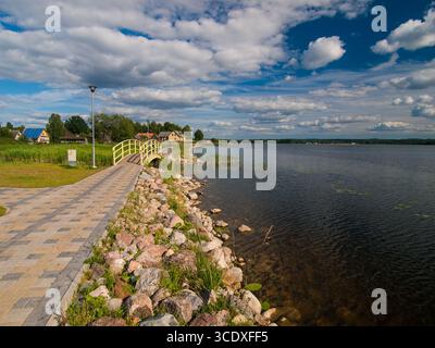Juillet 2010, Võru, Estonie : promenade au bord du lac Tamula avec passerelle pavée, pont jaune et nuages d'été. Banque D'Images