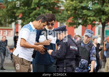 Des policiers russes vérifient les documents des migrants sur la place Rouge Banque D'Images
