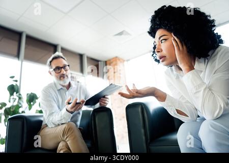 Dialogue professionnel entre collègues dans un espace de travail moderne avec des perspectives diverses et un environnement collaboratif Banque D'Images