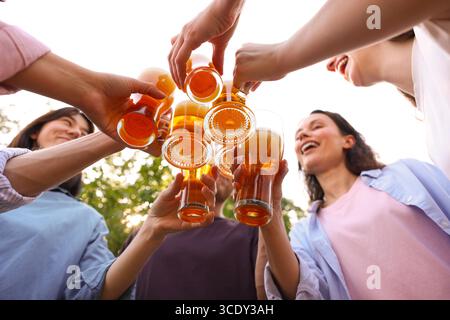 Groupe d'amis heureux clinquant des verres de bière à l'extérieur, vue de dessous Banque D'Images