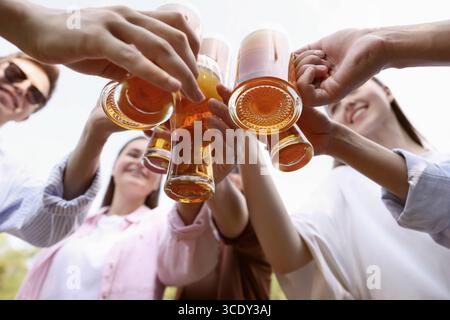 Groupe d'amis heureux clinquant des verres de bière à l'extérieur, vue de dessous Banque D'Images