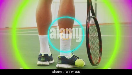 Afficher le bas des jambes portant des chaussettes, des chaussures marine sur un court de tennis, avec raquette, balle et anneaux néon. Athlétique, sport, fitness, vêtements d'action, compétition, Banque D'Images