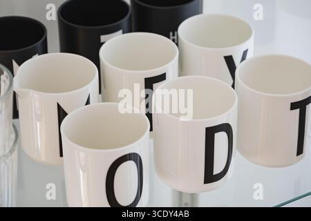 Tasses minimalistes en noir et blanc avec des impressions de lettres audacieuses sur l'étagère Banque D'Images