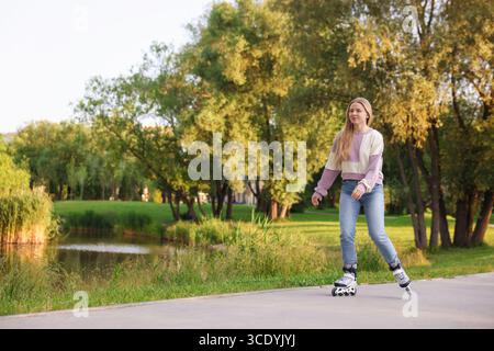 Belle jeune femme patin à roulettes dans le parc Banque D'Images