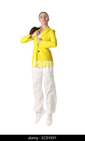 Femme en veste jaune sautant sur fond blanc Banque D'Images