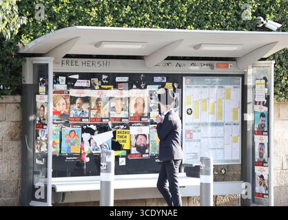 Des gens marchent devant un arrêt de bus couvert d’affiches d’otages à Jérusalem le 26 février 2025. Photo de Raquel G. Frohlich. Banque D'Images