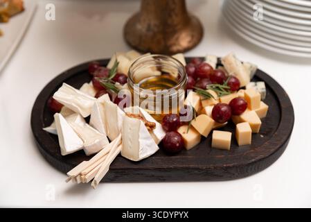 Un plateau magnifiquement arrangé avec une variété de fromages, raisins et miel, idéal pour les rassemblements. la combinaison de saveurs et de textures crée Banque D'Images