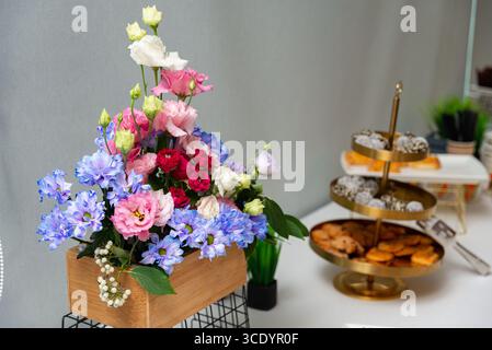 Un arrangement floral magnifiquement conçu avec des fleurs roses, rouges et bleues vibrantes. complétant les fleurs, un plateau à plusieurs niveaux offre une sélection de Banque D'Images