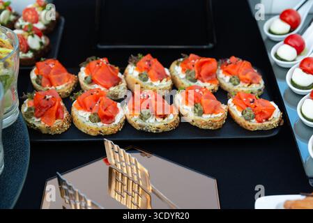 Sélection d'élégants canapés garnis de saumon fumé, de câpres et de fromage à la crème. parfait pour la restauration lors d'événements ou de rassemblements sophistiqués Banque D'Images